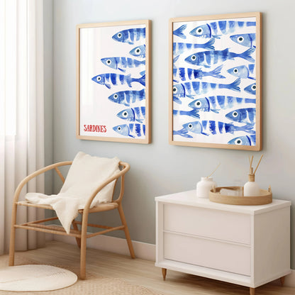 Two framed artworks of blue fish on a wall above a chair and cabinet.
