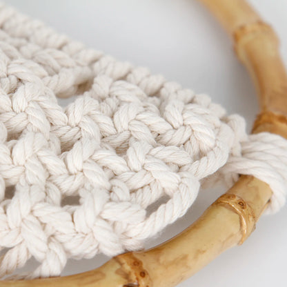 Close-up of a white knitted rope with a bamboo handle on a light background