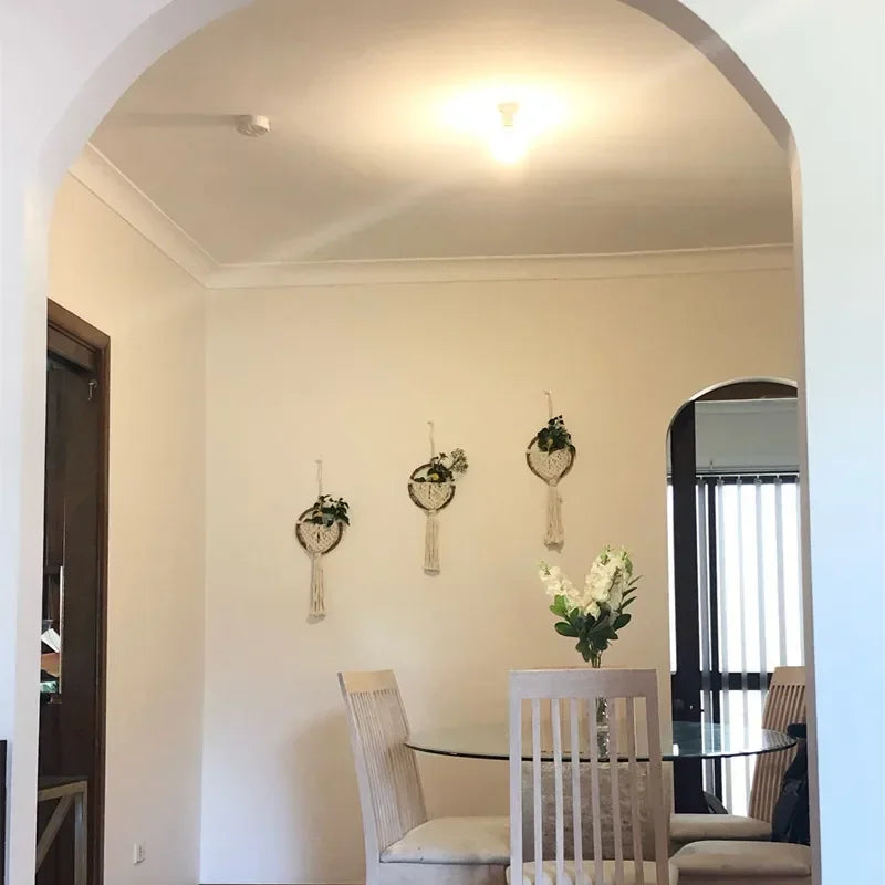 Dining room with a round glass table and chairs, wall decorations, and a window.